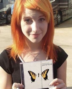 a girl with orange hair holding up a butterfly shaped book in front of her face