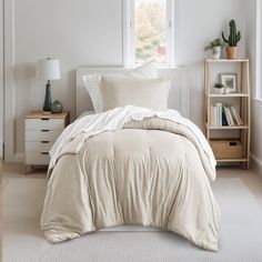 a bedroom with white walls and beige bedding