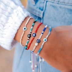 The Beaded Evil Eye Bracelet is more than just a piece of jewelry. With its ancient protective symbol and blue beads, it helps promote peace, confidence, and clarity. Say goodbye to bad omens and hello to a stylish and positive accessory. This stunning Beaded Evil Eye Bracelet features blue, white and cream colored beads with a translucent Evil Eye bead in the center. This Beaded Evil Eye Bracelet features an adjustable size cotton cord fitting wrists sizes from 6.5 - 8.5". Elevate your look and Blue Spiritual Friendship Bracelets For Festivals, Bohemian Blue Friendship Bracelets With 8mm Beads, Bohemian Evil Eye Bracelet For Friendship, Spiritual Blue Friendship Bracelets For Festivals, Blue Spiritual Festival Friendship Bracelets, Adjustable Symbolic Beaded Bracelets, Blue Spiritual Braided Bracelets Hand-strung, Bohemian Evil Eye Bracelet With Round Letter Beads, Bohemian Evil Eye Bracelet With Letter Beads