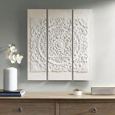 a white vase sitting on top of a wooden dresser next to two large pieces of art