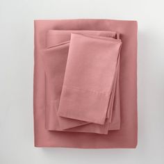 pink sheets folded on top of each other in front of a white wall with two vases