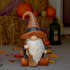 a gnome statue sitting on top of a wooden floor next to pumpkins and hay