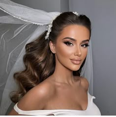 a woman wearing a wedding veil with her hair in a ponytail and makeup on her face