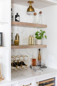 the shelves in this kitchen are filled with wine bottles and glasses, along with other items