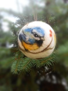 an ornament hanging from a tree with a bird painted on it's face