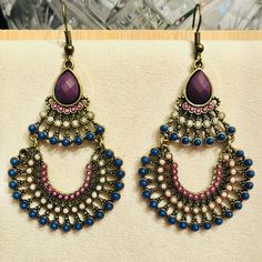 Add A Touch Of Bohemian Retro Charm To Your Outfit With This Stunning Set Of 3" Bronze-Tone Earrings. The Earrings Feature A Drop Dangle Design In Gorgeous Shades Of Purple, Pink And Blue. Crafted With Care, These Handcrafted Pieces Are Perfect For Adding A Unique Touch To Any Outfit. Whether You're Dressing Up For A Special Occasion Or Just Adding A Pop Of Color To Your Everyday Look, These Earrings Are Sure To Turn Heads. This Set Is Brand New And Ready To Be Worn. Don't Miss Out On The Chance Multicolor Teardrop Bohemian Jewelry, Bohemian Multicolor Teardrop Jewelry, Traditional Purple Jewelry For Festival, Purple Traditional Festival Jewelry, Purple Teardrop Metal Jewelry, Multicolor Metal Dangle Chandelier Earrings, Nickel Free Purple Earrings For Festival, Blue Earrings With Colorful Metal Beads, Nickel-free Purple Earrings For Festival