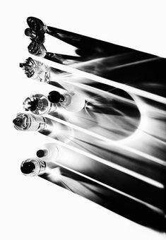 black and white photograph of four wine bottles with the tops turned upside down in motion