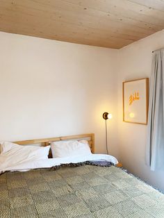 a bed sitting in a bedroom next to a window with curtains on the windowsill