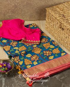 a blue and pink saree sitting on top of a table next to a basket