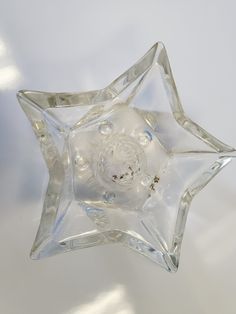 a clear glass star ornament sitting on top of a white tableclothed surface