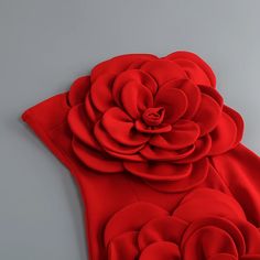 a red dress with large flowers on the front and back, is displayed against a gray background