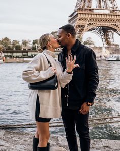 a man and woman kissing in front of the eiffel tower