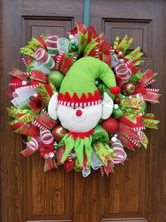 a christmas wreath on the front door with an elf's hat hanging from it