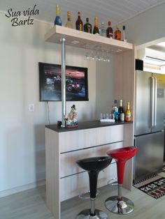 a bar with two stools in front of it and bottles on the top shelf