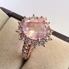 an engagement ring with a pink stone surrounded by white and brown diamonds in a box