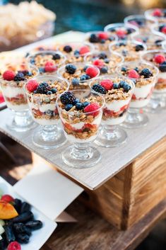 desserts are arranged in small glass dishes on a table with fruit and other foods