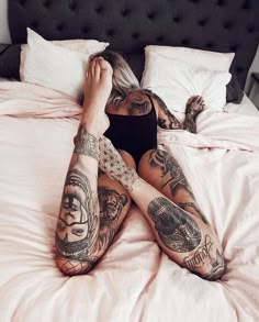 a woman laying on top of a bed covered in lots of tattooed arms and legs