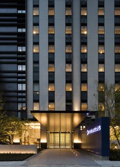 the entrance to a hotel at night with lights shining on it's windows and trees