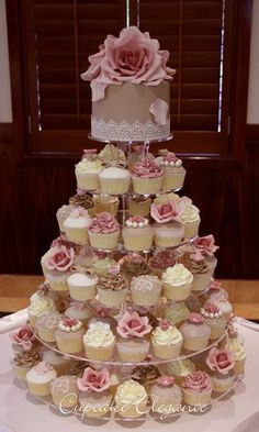 a three tiered cake with cupcakes on the bottom and pink flowers on top