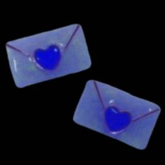 two blue hearts are in an envelope on a black background and one has a string attached to it