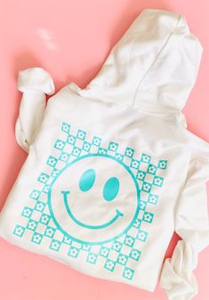 Woman & Girl Sweater | Girls Sweatshirt | Adult Sweater | Mama Sweatshirt | Smiley Face Sweater  Gildan Unisex Adult/Youth Heavy Cotton Long Sleeve Sweatshirt, it has a design in Black HTV (Heat Transfer Vinyl) Design: Front: Smiley face (pocket size) Back: Checkered Smiley face  Important: The dimensions of the designs will be proportional to the size of the Sweater. Available Sweatshirt colors:   - White    - Sport Grey     - Black   Details: The Gildan 18000 Adult Sweatshirt is made from a he Trendy White Hoodie Top, Printed White Top For Winter, White Hooded Top With Screen Print, Playful White Long Sleeve Sweatshirt, White Hoodie With Screen Print, White Screen Print Hoodie, White Graphic Print Hoodie For Loungewear, Playful White Hoodie For Winter, Playful Green Cotton Sweatshirt