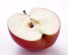 an apple cut in half on a white surface