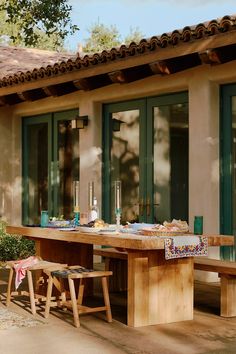 a wooden table sitting in front of a building with green doors and windows on it