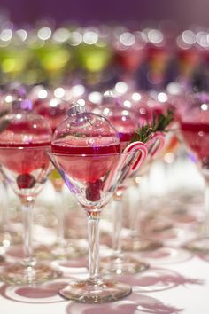 several glasses filled with different colored drinks on top of a white table covered in confetti