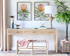 two paintings on the wall above a table with a bench and lamp next to it