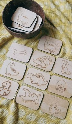 wooden coasters with carved images of animals and bones are on a yellow blanket next to a bowl