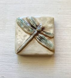 a ceramic dragonfly ornament sitting on top of a wooden table