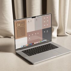 an open laptop computer sitting on top of a white table next to a pair of curtains