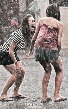 two girls laughing while standing in the rain