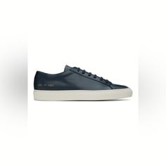 Low-Top Buffed Leather Sneakers In Navy. Signature Series Stamp At Outer Side. Lace-Up Closure Padded Tongue And Collar Suede And Buffed Leather Lining Treaded Rubber Sole Modern Blue Custom Sneakers With Vulcanized Sole, Modern Navy Sneakers With Round Toe, Sporty Navy Sneakers With Leather Sole, Blue Sneakers With Rubber Heel Cap For Sports, Blue Low-top Sneakers With Leather Sole, Luxury Low-top Custom Sneakers With Rubber Heel Cap, Navy Low-top Sneakers With Textured Sole, Classic Navy Sneakers With Contrast Sole, Classic Navy Sneakers With Textured Sole