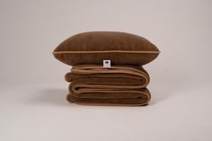 three pillows stacked on top of each other in front of a white background with a tag