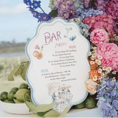 there is a sign that says bar menu next to some flowers and other things on the table