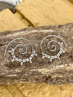 two silver earrings sitting on top of a rock