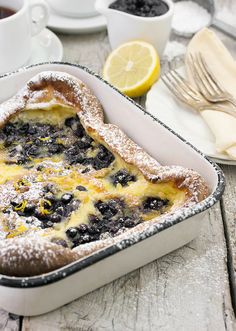 a casserole dish with blueberries and powdered sugar in it on a table