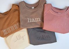 four different colored shirts with the names of three children's sweaters on them