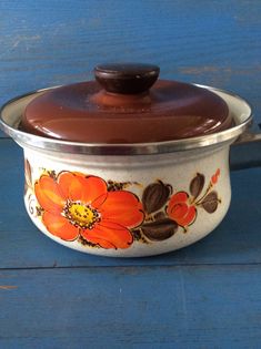 an orange flower painted on the side of a white casserole with a brown lid