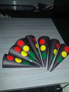 four black cones with red, yellow and green dots on them sitting on a table