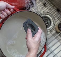 a person is washing dishes in a red pan