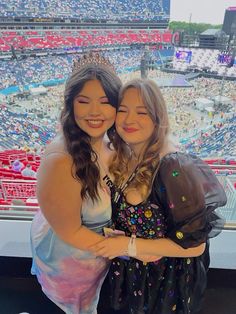 two girls are hugging each other in front of an arena full of people at a sporting event