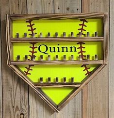 a wooden frame with baseballs and the word quinn on it in front of a wood wall