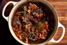 a pot filled with meat and vegetables on top of a wooden table