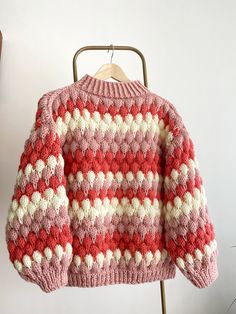 a red and white sweater hanging on a clothes rack