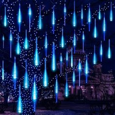 many blue lights are hanging from the trees in front of a building at night time