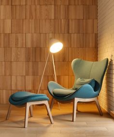 a chair and foot stool in front of a brick wall with a lamp on it