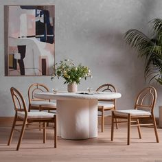 a dining room table with chairs and a potted plant in the corner next to it