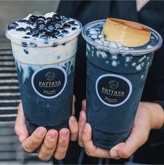 two people holding up drinks with blueberries on top and ice cream in the middle